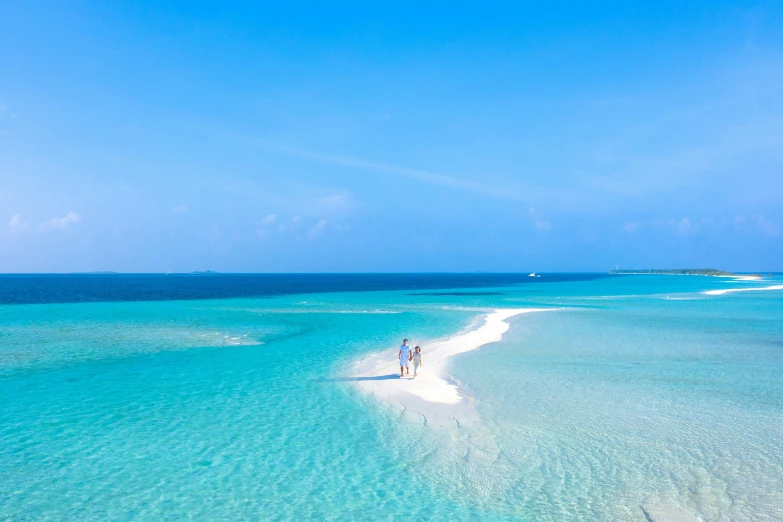 couple on beach in shallow blue ocean waters