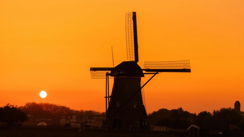 a windmill in the middle of a field at sunset