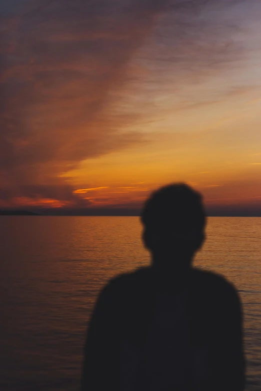 the person is watching the sun set by the water