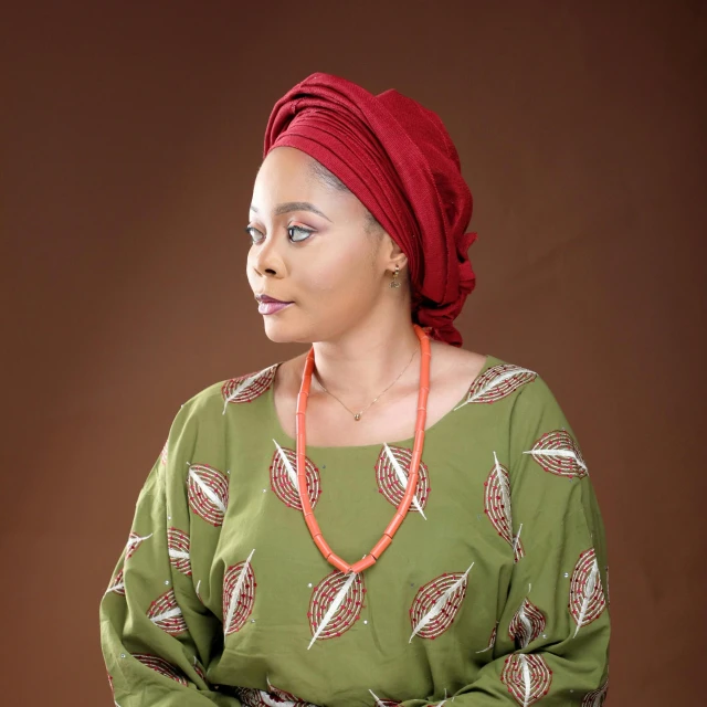 a woman with a red head scarf sits in front of brown background