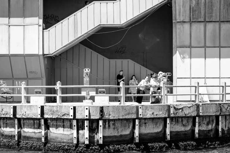 people are standing by a gate near some water