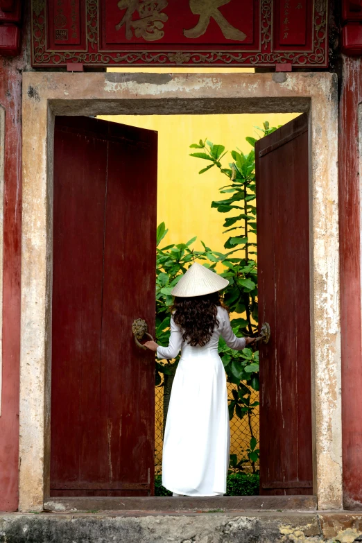 woman wearing white dress and straw hat outside of doorway