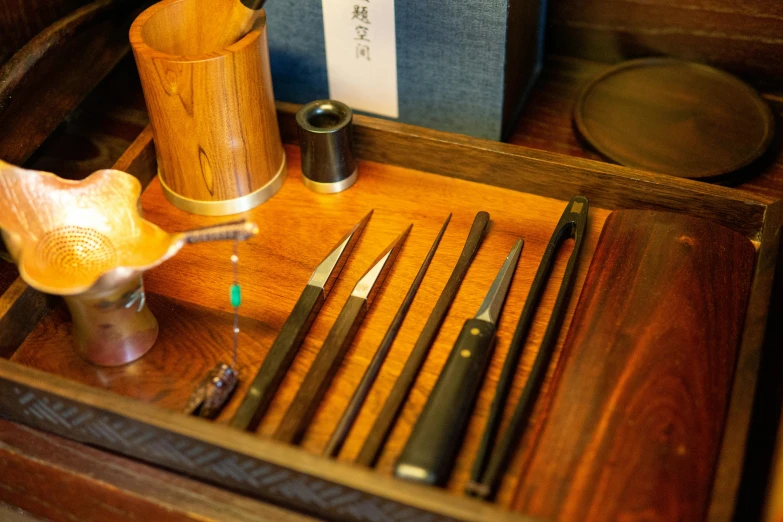 a wooden drawer with knives, spoons, and other items on it