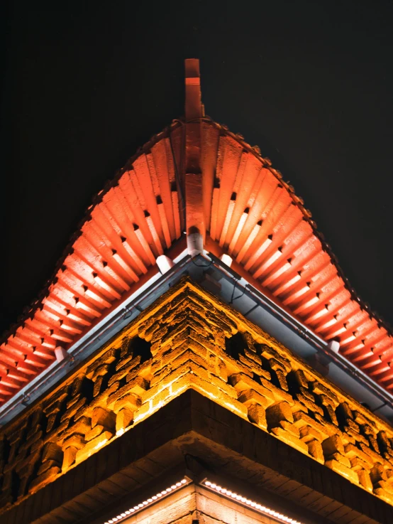 the top of a building is lit up by lights at night