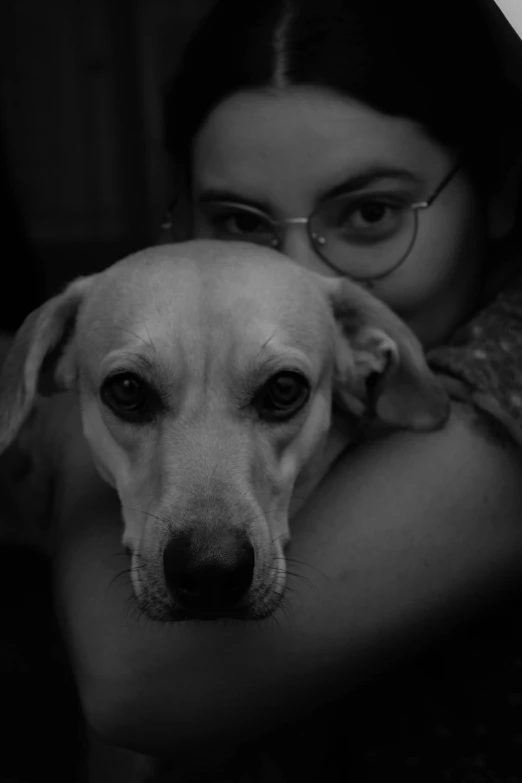 a woman is hugging her dog on her lap