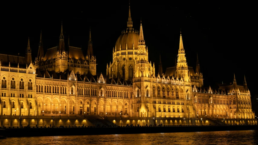 a castle that is lit up at night with people on the water