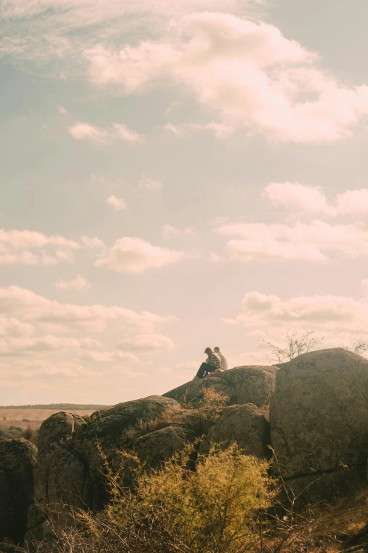 two men sitting on the rocks outside