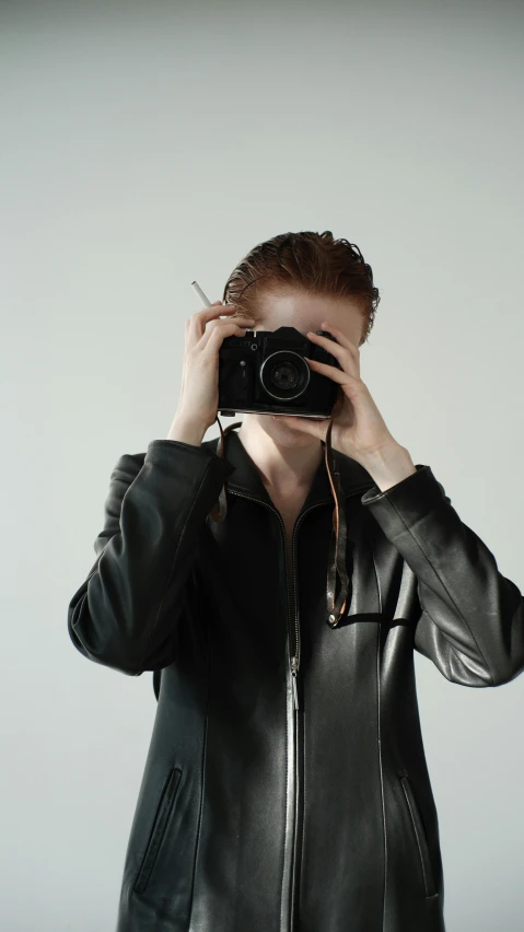 a woman in leather jacket taking a picture with a camera