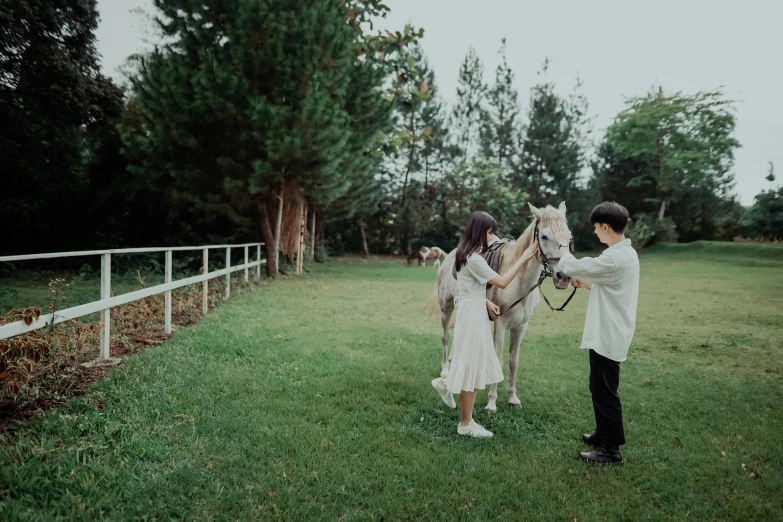a man and woman petting a horse near a white fence