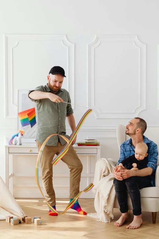 a man and a woman standing near a baby with a kite in their hands