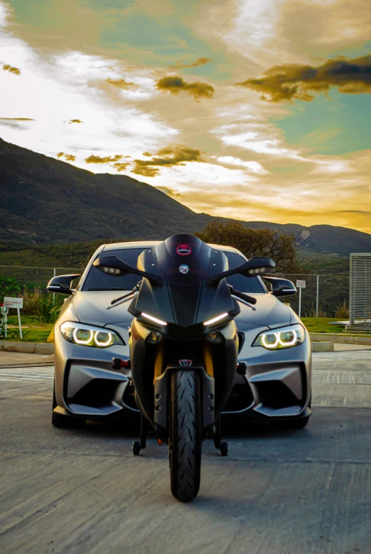 two motorcycles parked side by side with the sun setting