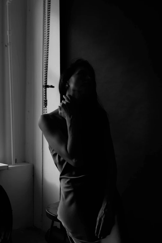 a woman in lingerie leaning against a window sill