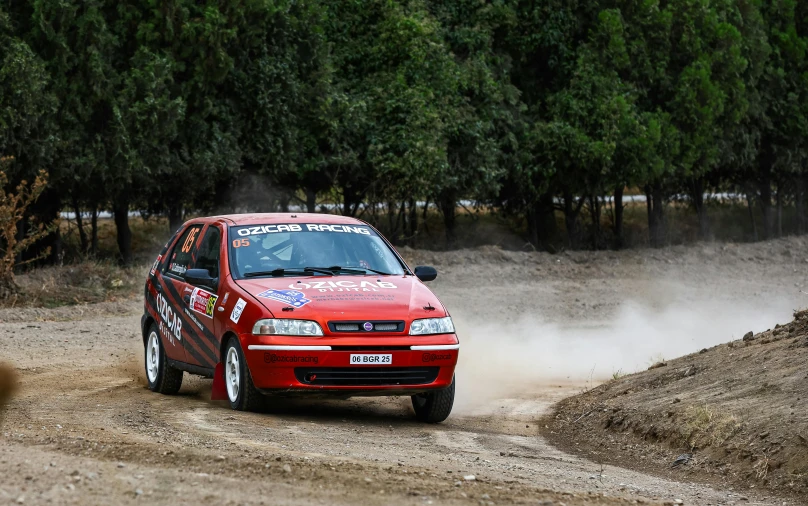 a red and white vehicle is driving in the dirt