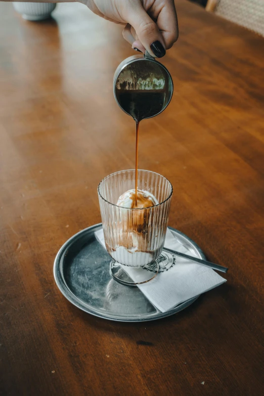 a person stirring sauce onto a cup of food