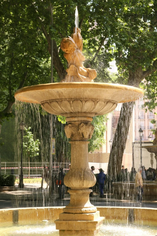 a water fountain in a park has a man statue on the top