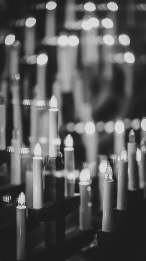 many candles on a table with a wall of lights behind them