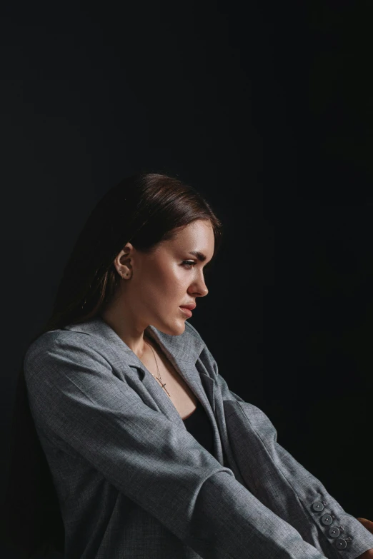 woman sitting in front of black background with her hands resting on her lap