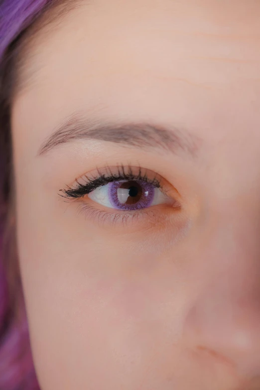 a woman with purple hair and bright blue eyes looking off in the distance