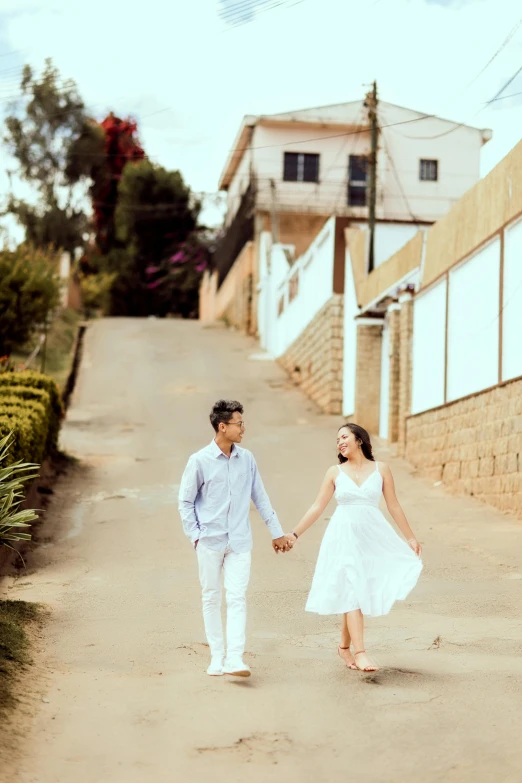 couple walking hand in hand down path between two buildings