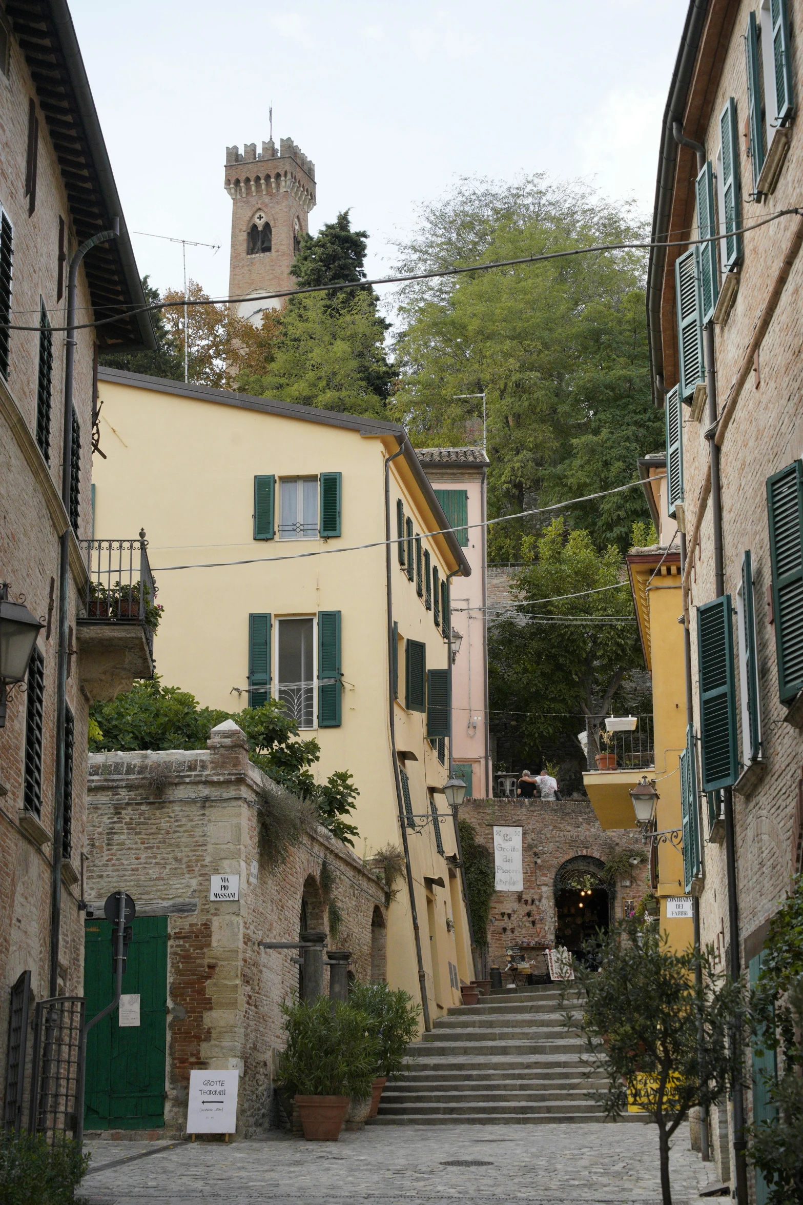 a steep stone stairway has green shutters and green windows