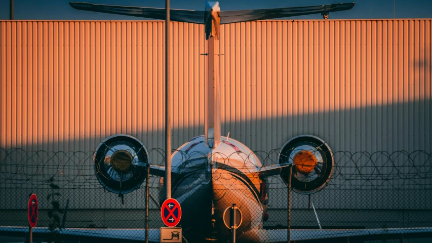 a plane sitting outside of a building near a fence