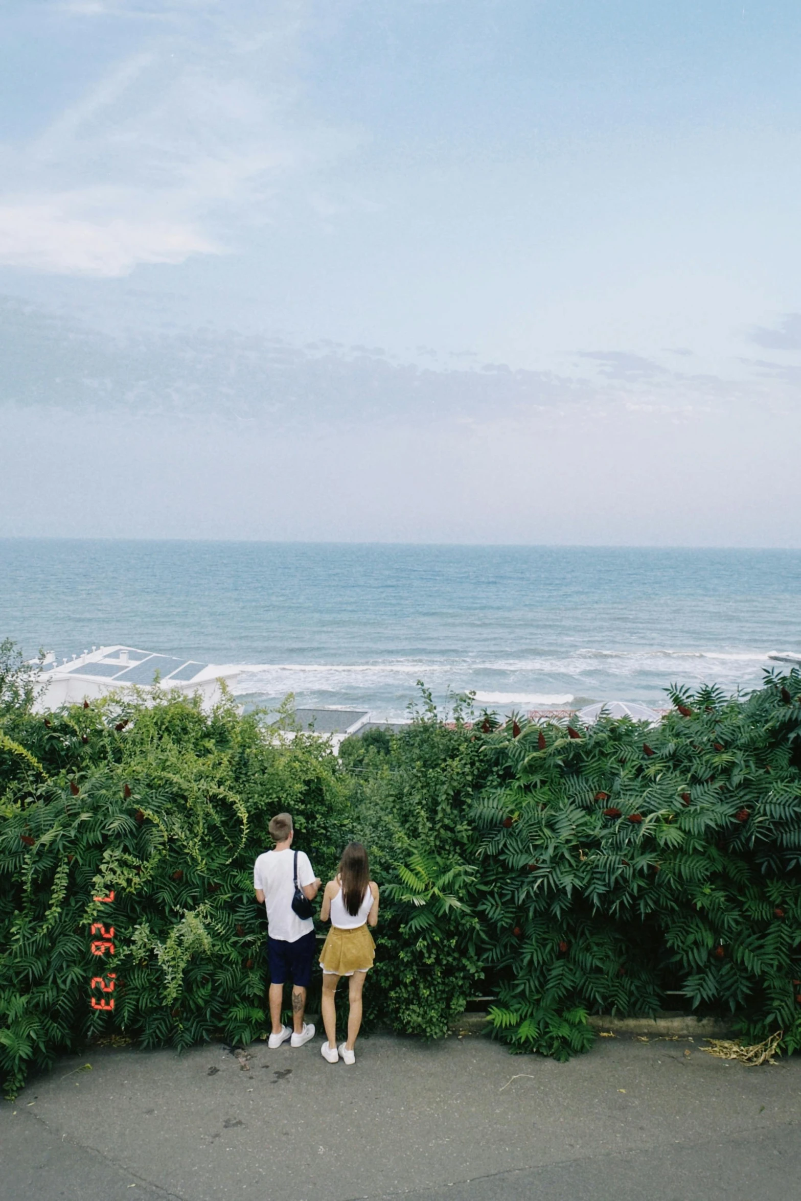 two people standing at the top of a hill overlooking a vast ocean