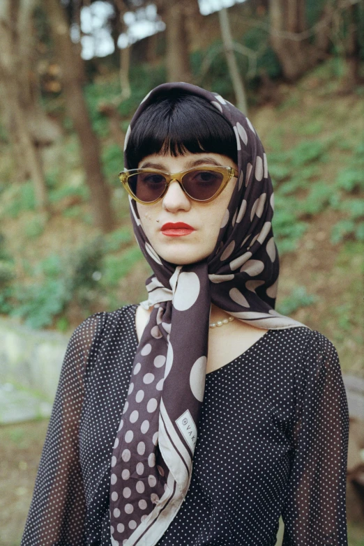 a woman is wearing sunglasses and a scarf