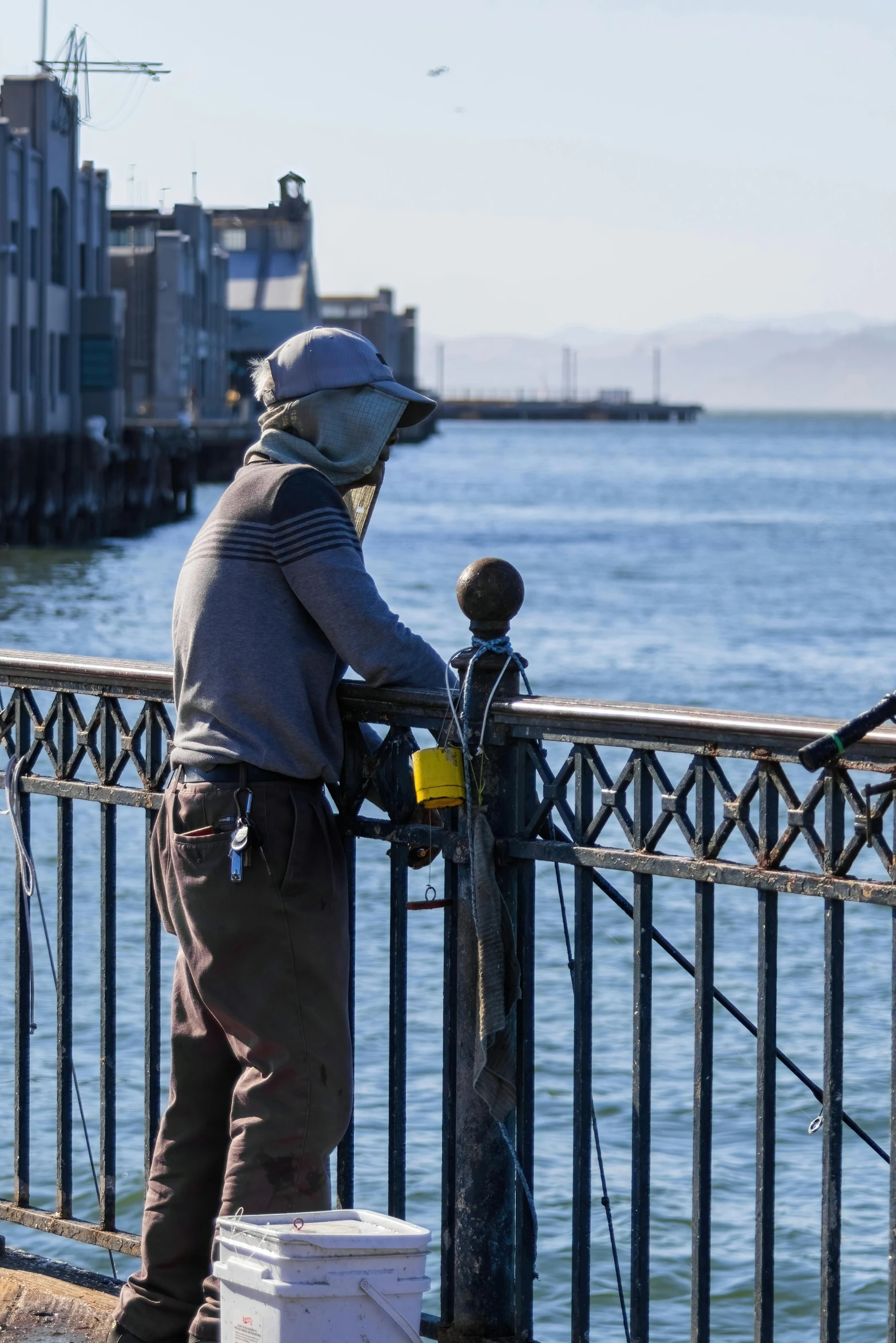 a man with his hands on a gate with the ocean in the background