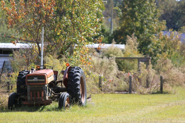 an old orange tractor sits in a field