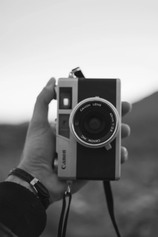 someone holding an old camera with a large lens