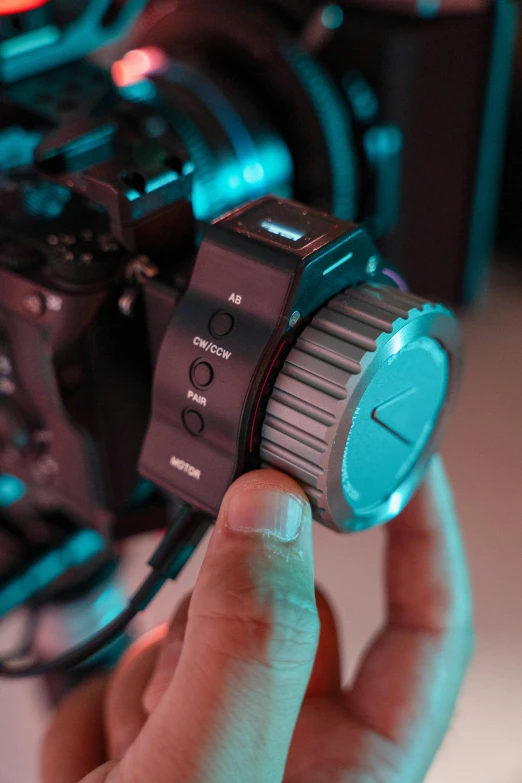 a hand holding a camera near some strings