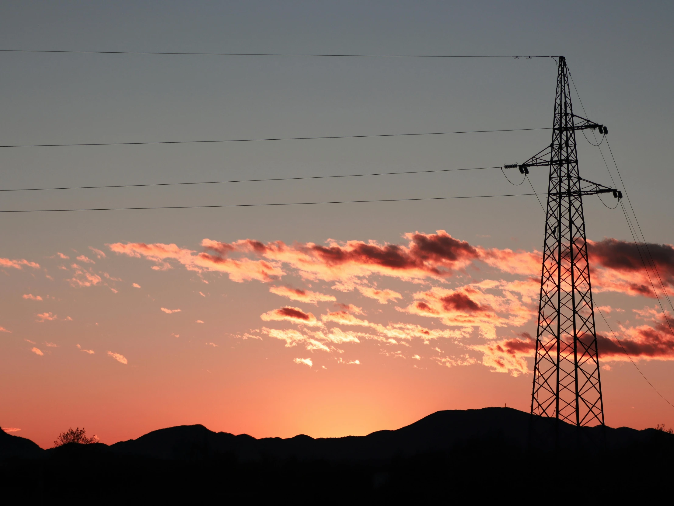 the silhouette of electrical lines with the sun setting