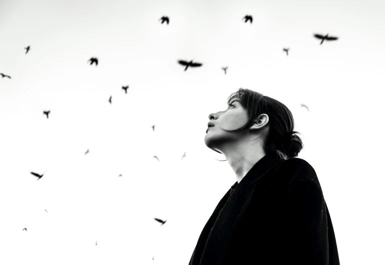 a man staring up at birds flying overhead