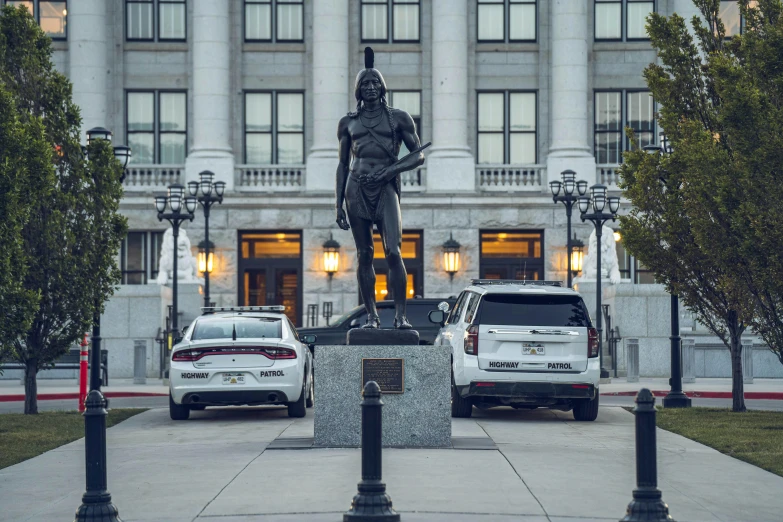 cars and a statue in front of a building