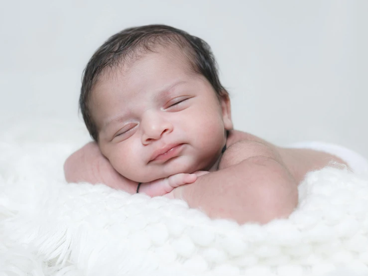 a newborn baby is sleeping on white fur