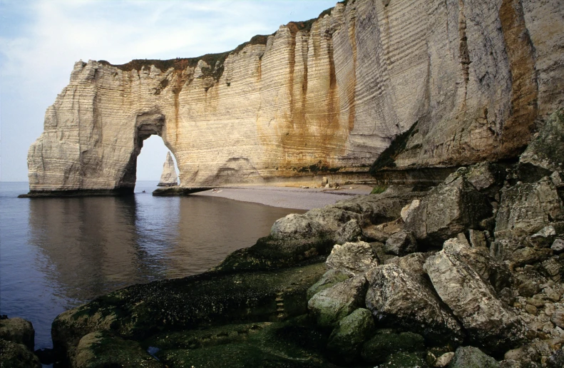 a large rocky body of water with an arch at the edge