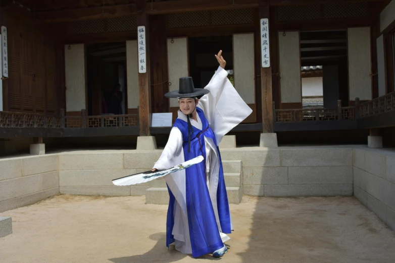 a woman wearing a hat and dress and holding a badminton racquet