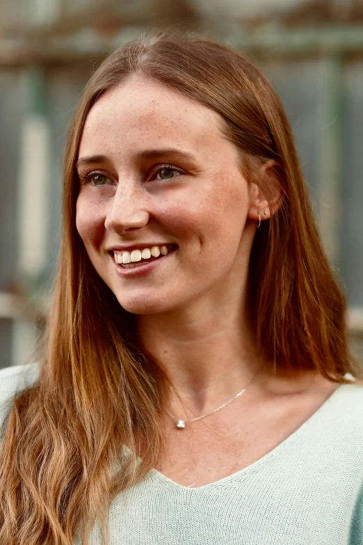 a smiling woman with bangs on a white top