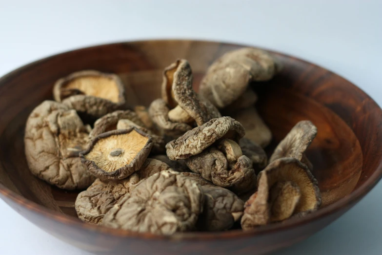 some brown mushrooms are in a wooden bowl