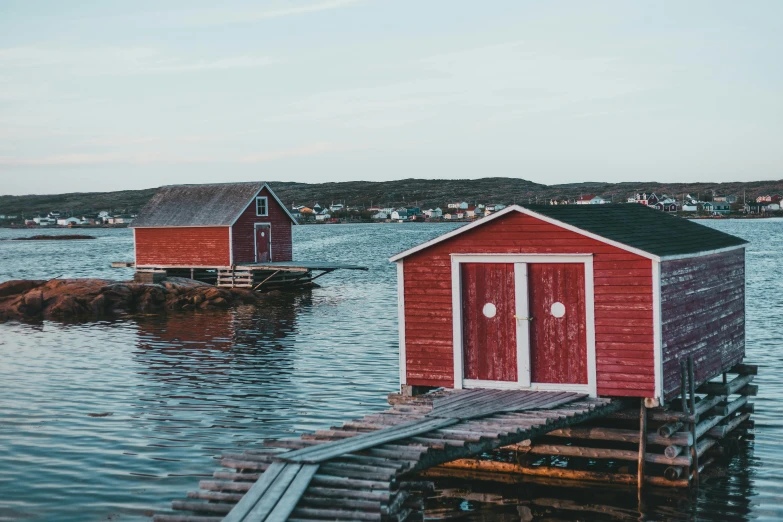 two red huts sitting on the water next to a dock