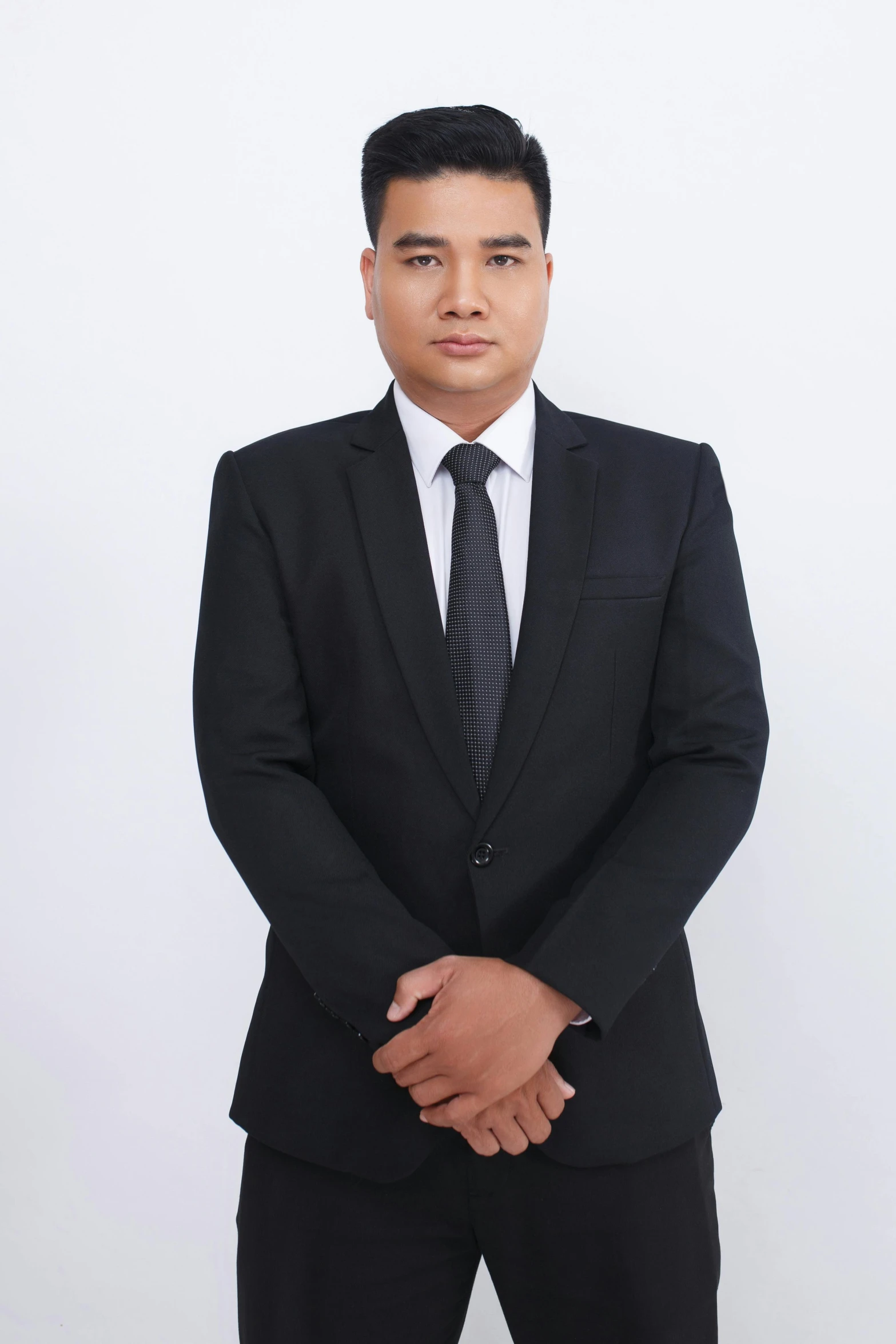 a man wearing a black suit standing in front of a white background