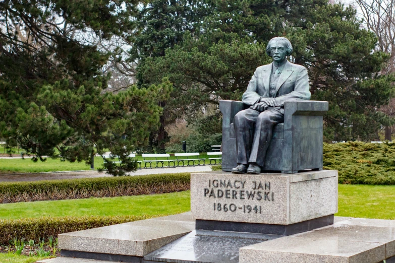 a statue of a man sitting in a box in the middle of a park