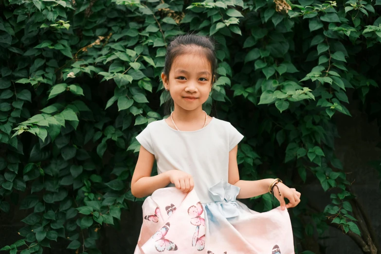 a small girl stands holding onto her pink floral bag