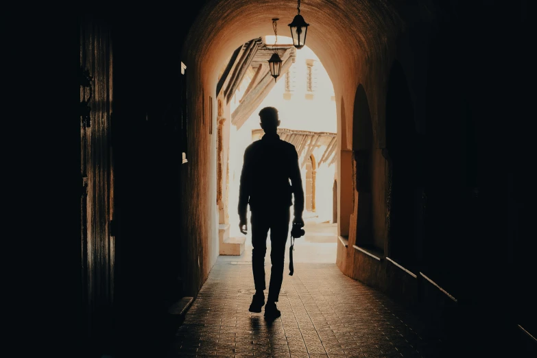 a man is walking towards the camera through an archway