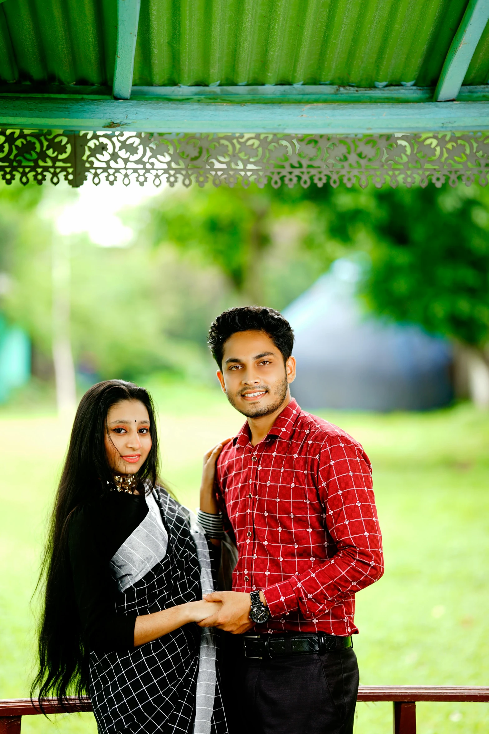 a beautiful couple pose together under a gazebo in their backyard