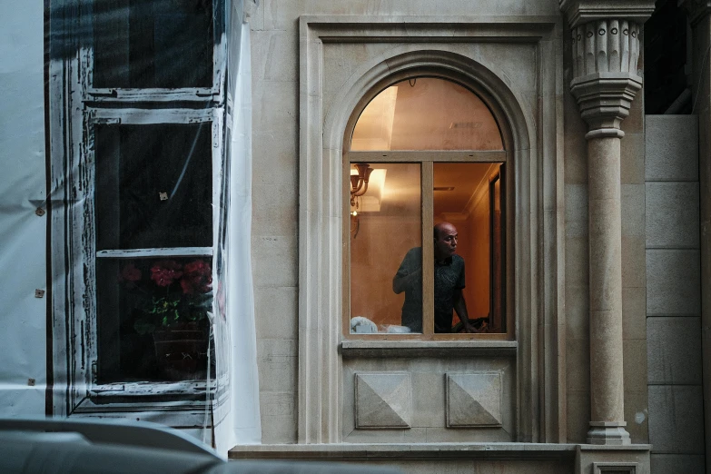 a man standing outside of a building with a window open