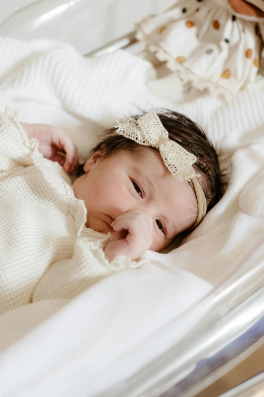 a baby girl laying in her bed with a white blanket