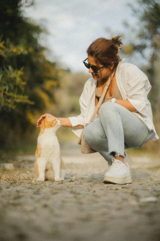 a woman pets her cat outside while sitting on the ground