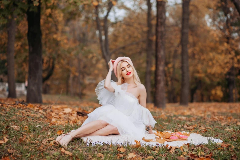 a woman dressed in white posing on a blanket with her hands up