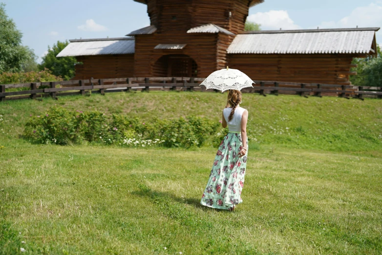 woman in floral dress standing on the grass holding an umbrella